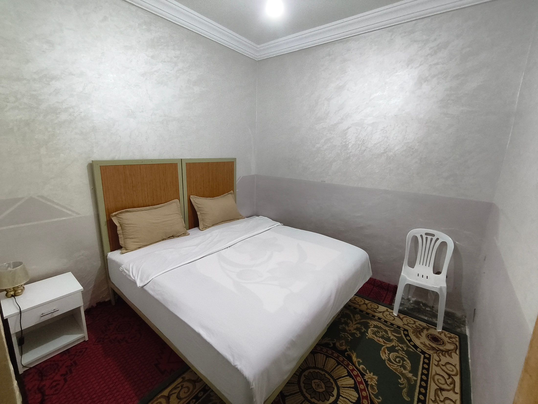 Room 3 at Aziz House: a double bed with white linen against a soft grey wall