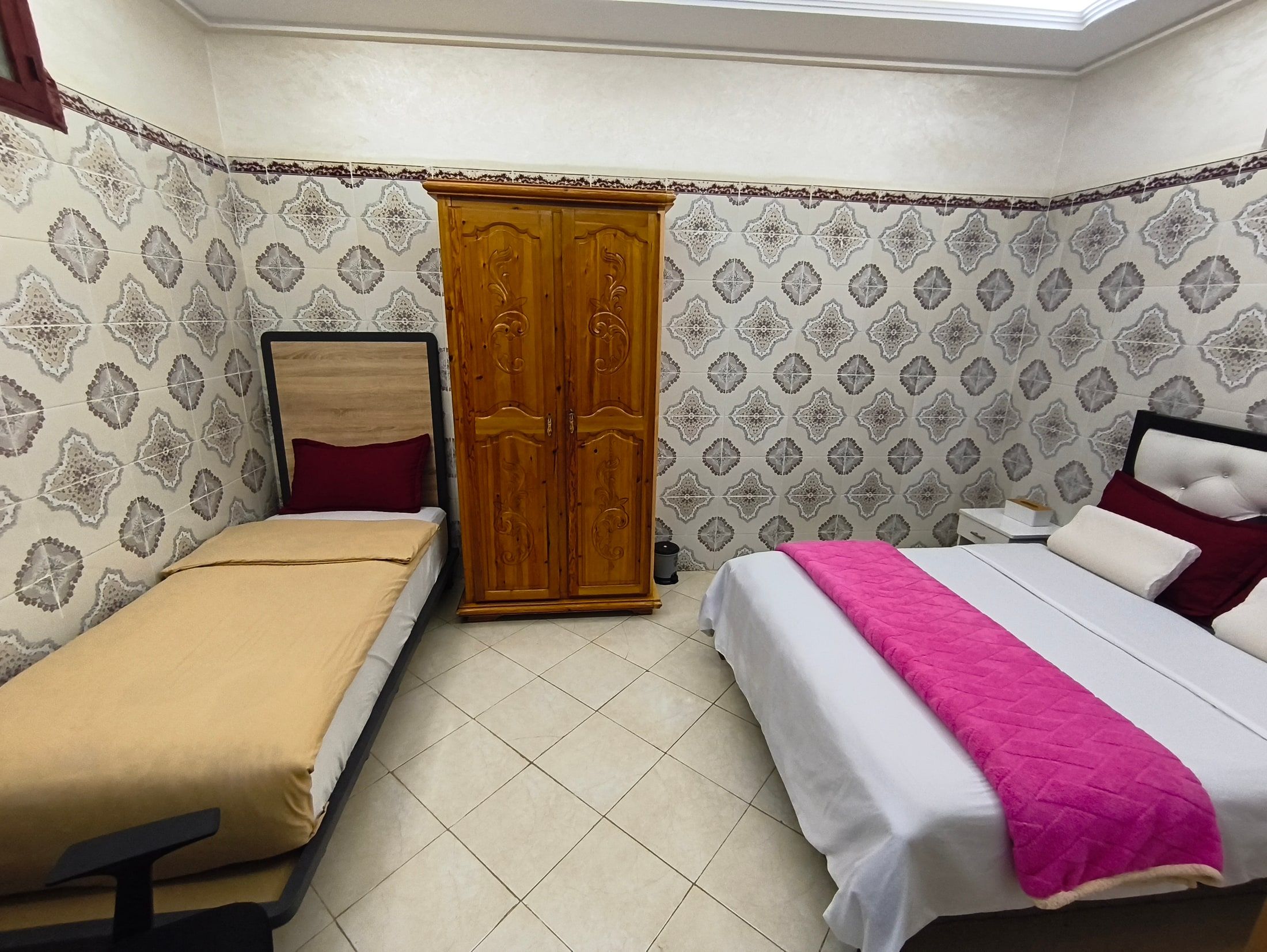 Room 2 at Aziz House: a single bed, a wooden wardrobe and a double bed with a pink throw