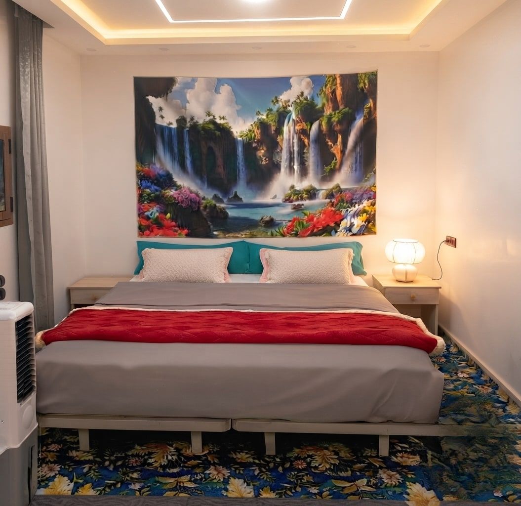 Le grand lit double de la chambre 1, sous un panneau mural peint