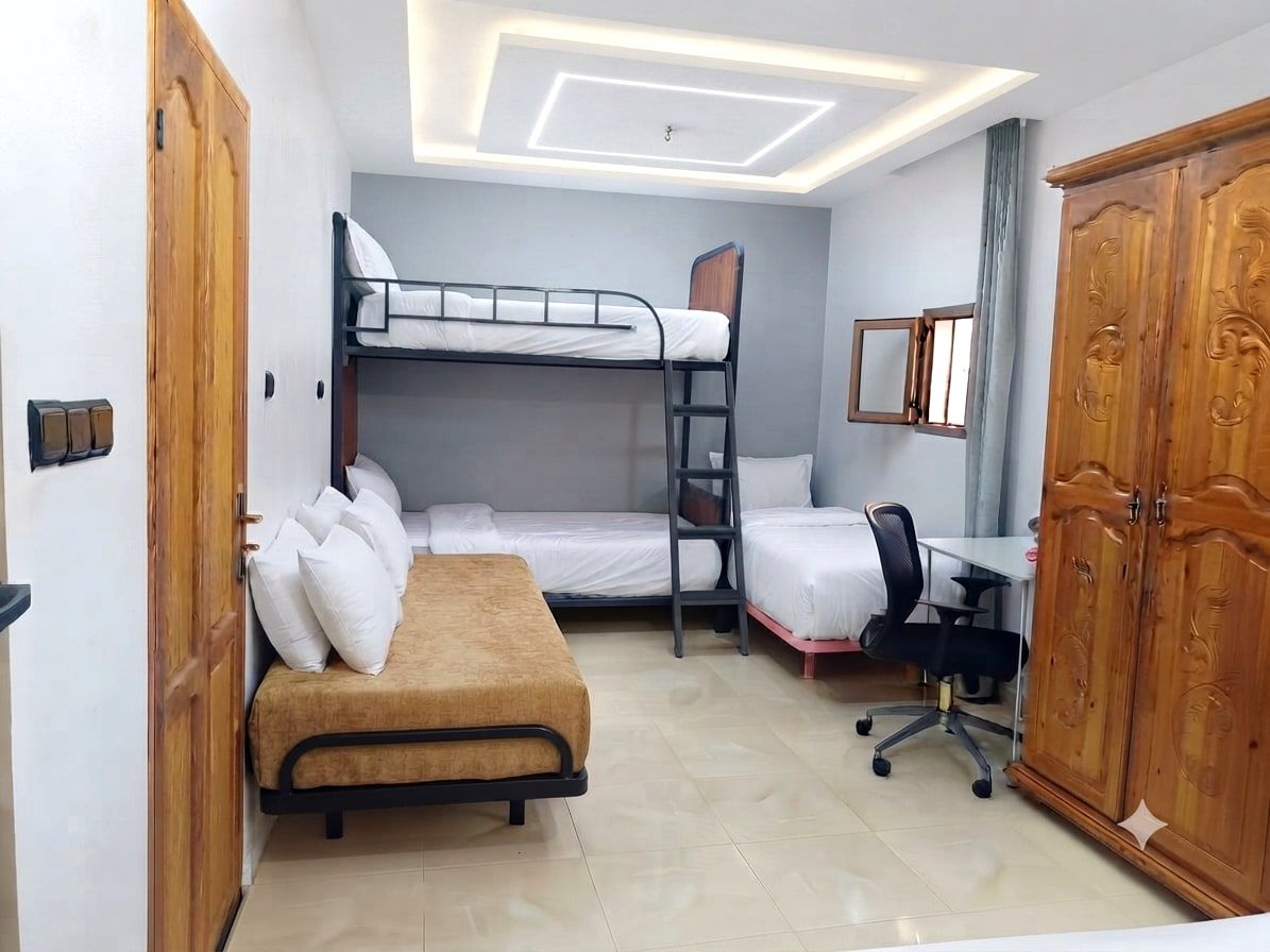 Les lits simples supplémentaires et le lit superposé de la chambre 1, avec un canapé et un bureau