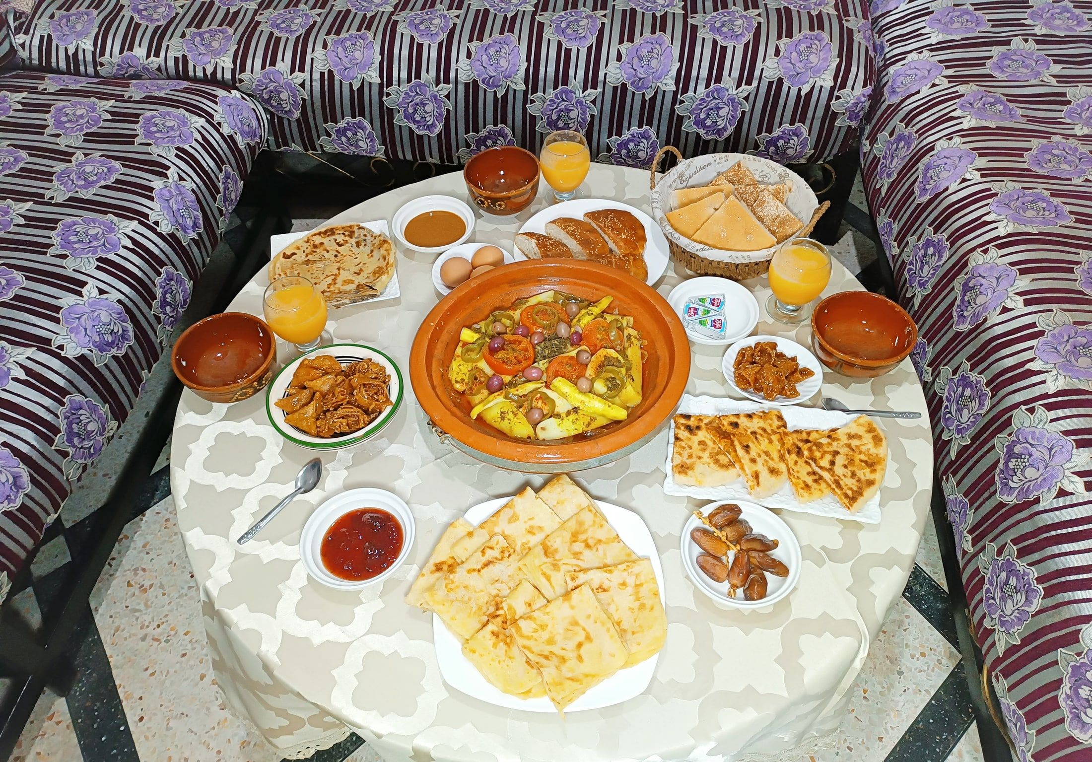 A Moroccan tagine with bread and side dishes served on a round table in the lounge