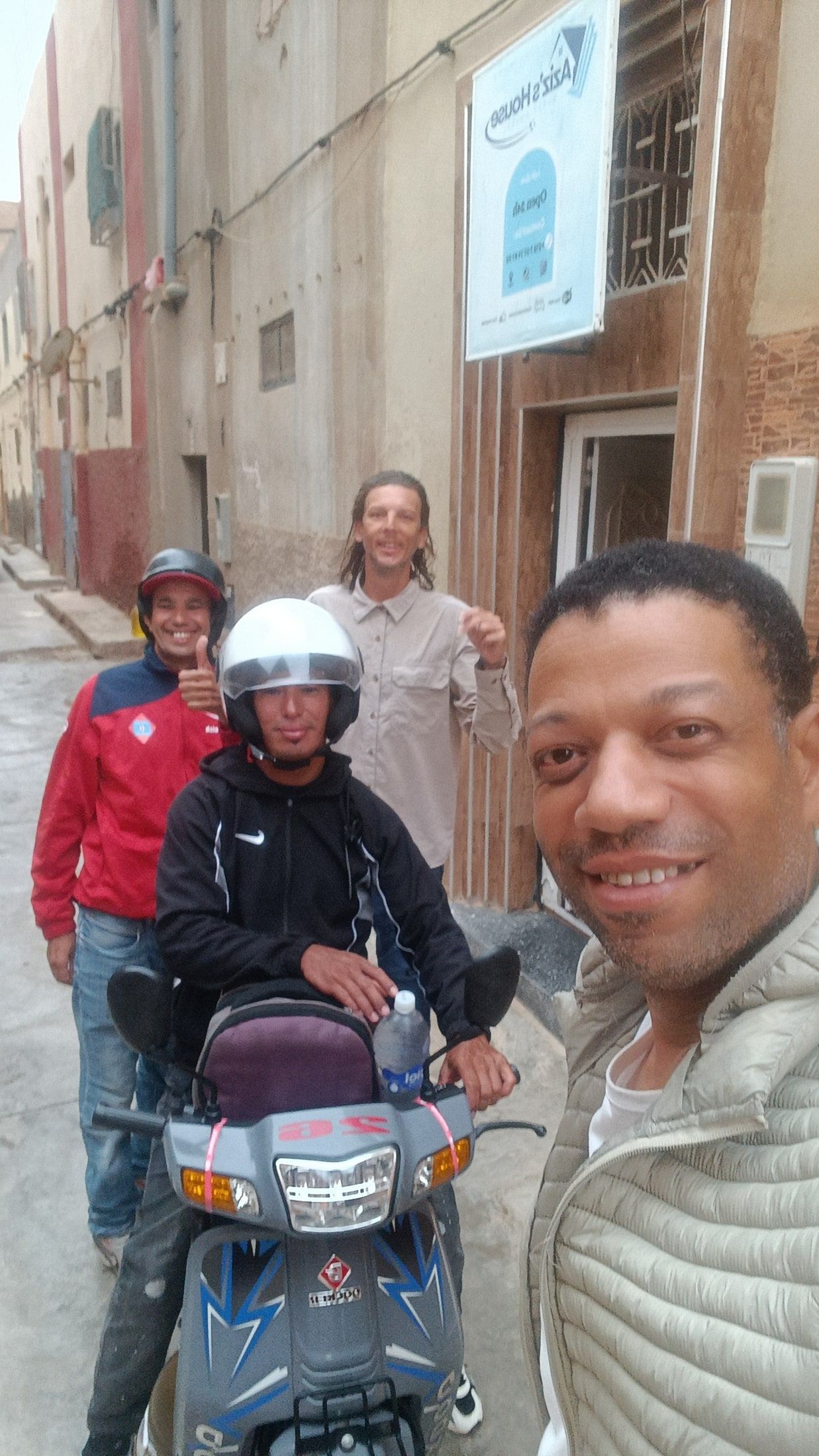 Aziz, the host, with guests and their scooter in the street outside Aziz House