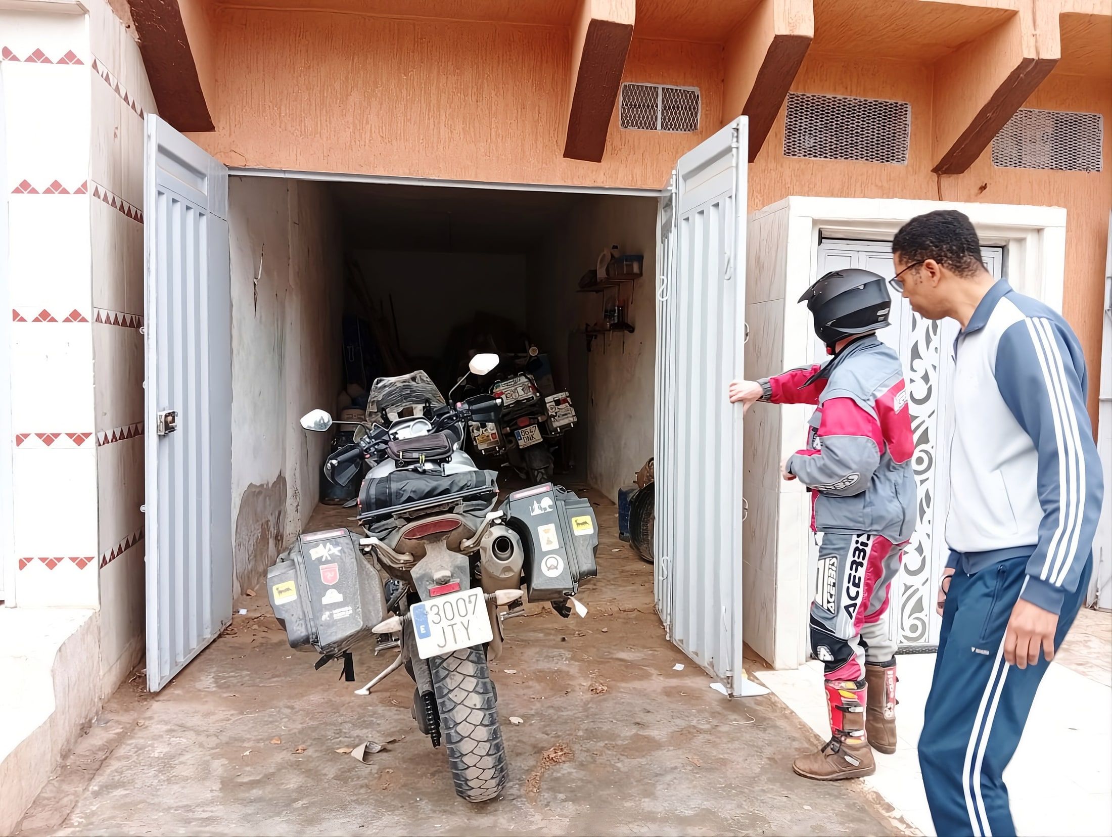 A traveller parking a loaded adventure motorcycle inside the private closed garage at Aziz House